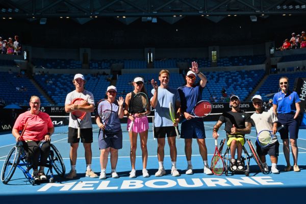 All abilities tennis players stand in a line on a tennis court