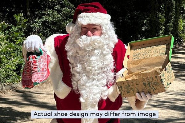 Santa holds a pair of Brooks runners and box. Text reads: actual shoe design may differ from image