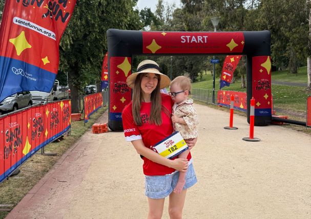 Client case study Finn being held my his mum at the Santa Fun Run start line Client case study Finn being held my his mum at the Santa Fun Run start line