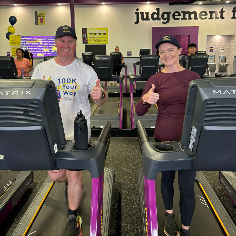Vision Australia client Dale wearing a 100K Your Way T-shirt, walking on the treadmill and giving a thumbs up sign with Ballarat Mayor, Cr Tracey Hargreaves. 