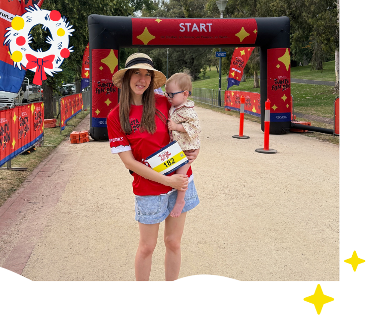 Vision Australia client Finn is being held in his mum's arms at the start line of the Santa Fun Run. Vision Australia client Finn is being held in his mum's arms at the start line of the Santa Fun Run.