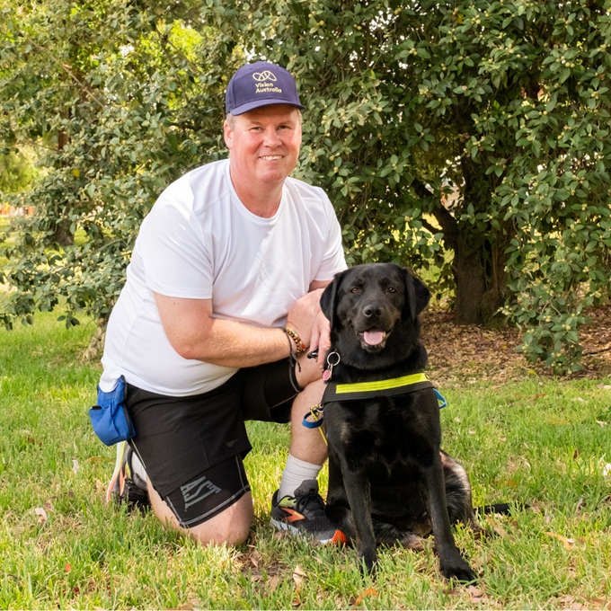 Dale kneeling on the grass with his seeing eye dog Yana