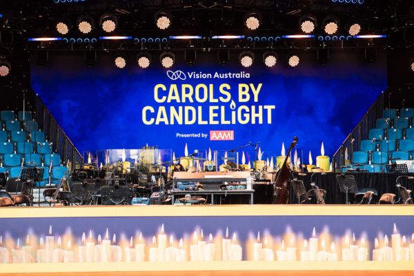 Carols by Candlelight stage showing an image of candles and the Carols by Candlelight logo