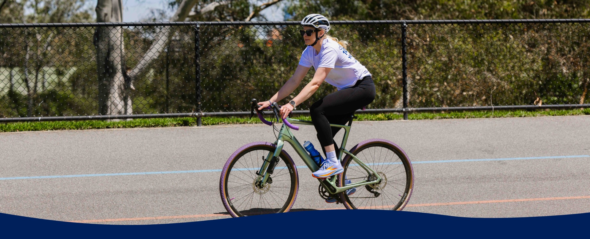Woman weats a helent and activewear riding a bike on bitumen